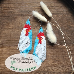 May include: A pair of long, triangular beaded earrings featuring a rooster design in white, red, and light blue beads. The earrings hang from silver-toned metal hooks. An oval label at the bottom reads Fringe Benefits Beading Co. PDF PATTERN.