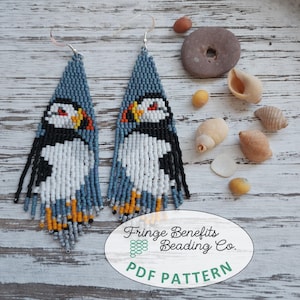 Peut inclure: Boucles d'oreilles en perles faites à la main représentant un macareux. Les boucles d'oreilles sont principalement bleues, blanches, noires et oranges, avec des franges en bas. Elles sont triangulaires et ont un crochet pour oreilles percées. L'image comprend des coquillages et le texte "Fringe Benefits Beading Co. PDF PATTERN."