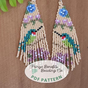 May include: A pair of beaded earrings with a fringe design. The earrings are made with beige, green, blue, and purple beads. The earrings are hanging from silver hooks. The image also includes the text "Fringe Benefits Beading Co. PDF PATTERN".