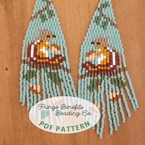 Puede incluir: Un par de aretes largos y abalorios con un diseño de flecos. Los aretes son de color azul turquesa, marrón y verde. Los aretes presentan una pequeña imagen de abalorios de una persona. Los aretes están etiquetados como "Fringe Benefits Beading Co. PDF Pattern".