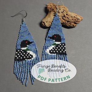 May include: Handmade beaded earrings featuring a loon design. The earrings are primarily blue with black, white, and red accents. The loon image is centered on the earrings, with a fringe of blue beads at the bottom. The earrings have silver-colored ear wires. The text "Fringe Benefits Beading Co. PDF PATTERN" is on the image.