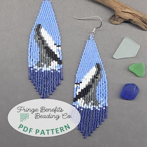 May include: Long, teardrop-shaped beaded earrings featuring a whale tail design in shades of light blue, dark blue, white, and gray. The earrings have a fringe bottom and silver-tone hooks. An oval label reads Fringe Benefits Beading Co. PDF PATTERN.