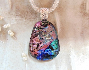 May include: A dichroic glass pendant with a teardrop shape, featuring iridescent swirls of pink, purple, blue, and green. The pendant is suspended from a silver-toned woven mesh chain by a textured, chevron-patterned silver-toned metal bail.