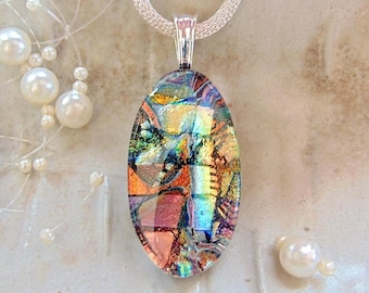 May include: An oval dichroic glass pendant featuring a multi-coloured mosaic pattern of iridescent orange, blue, green, and gold shards. The pendant is suspended from a silver-toned mesh chain and is surrounded by several loose white pearls.
