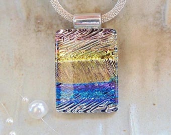 May include: A silver chain necklace with a rectangular glass pendant. The pendant has a layered design of iridescent colors, including pink, yellow, blue, and purple.