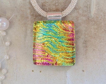 May include: A silver chain necklace with a rectangular iridescent glass pendant. The pendant has a wavy pattern in shades of yellow, green, blue, and pink.