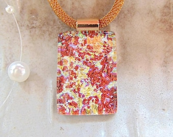 May include: A gold mesh chain necklace with a rectangular pendant. The pendant has a colourful, abstract design with red, yellow, and orange hues. A small gold clasp connects the pendant to the chain. A delicate pearl necklace is visible.