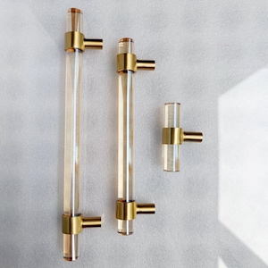 May include: Three gold and clear acrylic cabinet pulls. Two are long and have a single hole for mounting. The third is shorter and has two holes for mounting.