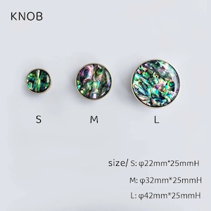 Op de afbeelding: Drie ronde kastknoppen met een gouden metalen basis en een iriserende parelmoer schelp inleg. De knoppen zijn verkrijgbaar in drie maten: klein, medium en groot. De tekst "KNOB" staat bovenaan de afbeelding. De tekst "size/ S: &phi;22mm*25mmH M: &phi;32mm*25mmH L: &phi;42mm*25mmH" staat onderaan de afbeelding.
