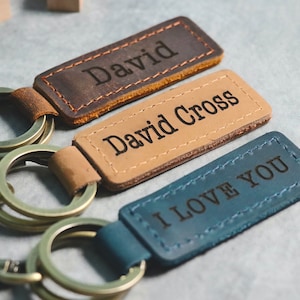 May include: Three leather keychains with metal rings. The first keychain is brown and says "David". The second keychain is tan and says "David Cross". The third keychain is blue and says "I Love You".