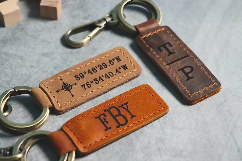 May include: Two leather keychains with engraved initials and coordinates. One keychain is brown with the initials "T|P" and the other is tan with the initials "FBY" and the coordinates "39&deg;46'29.6"N 75&deg;34'40.4"W".