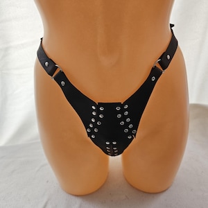 Op de afbeelding: Zwarte lederen lingerie met zilveren studs en verstelbare bandjes.