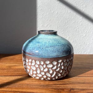 May include: A rustic wooden sign with the text "Welcome to our home" in white lettering. The sign features a distressed finish and a simple, inviting design, perfect for a front porch or entryway.