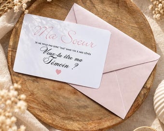 May include: A white rectangular card with rounded corners and a light pink envelope. The card features the text "Ma Soeur" in pink script, followed by "JE NE PEUX PAS DIRE "OUI" SANS TOI À MES CÔTÉS" and "Veux-tu être ma Témoin ?" in black, with a small pink heart.
