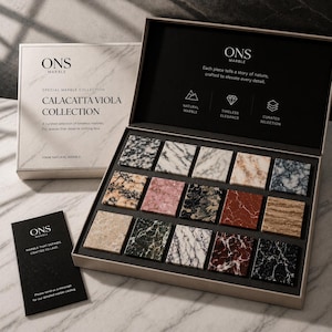 May include: A presentation box containing fifteen square 10mm natural marble samples in various colors and patterns. The box lid features the text ONS MARBLE CALACATTA VIOLA COLLECTION. A small black informational card with white text is included.
