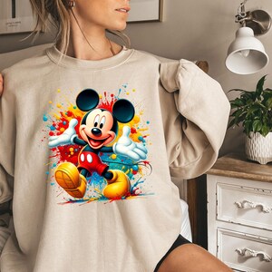 a woman wearing a sweatshirt with a mickey mouse graphic on it