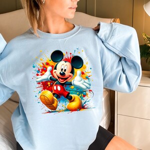 a woman wearing a blue sweatshirt with mickey mouse on it