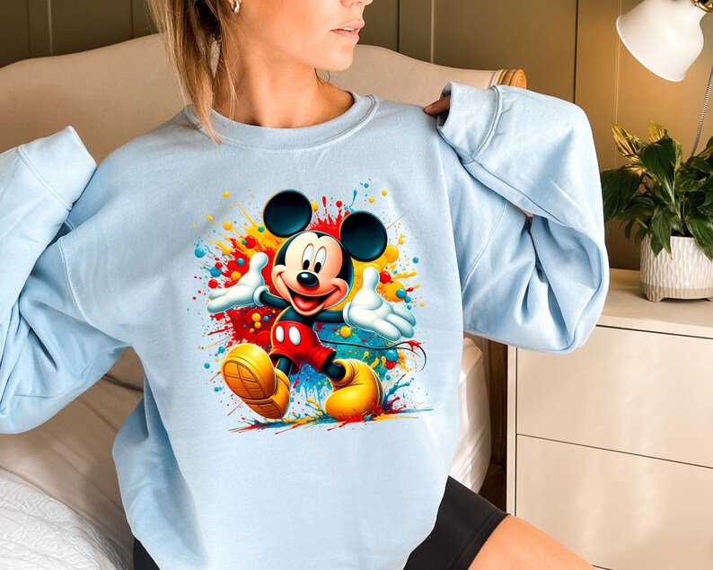 a woman wearing a blue sweatshirt with mickey mouse on it