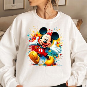 a woman wearing a sweatshirt with a mickey mouse painting on it