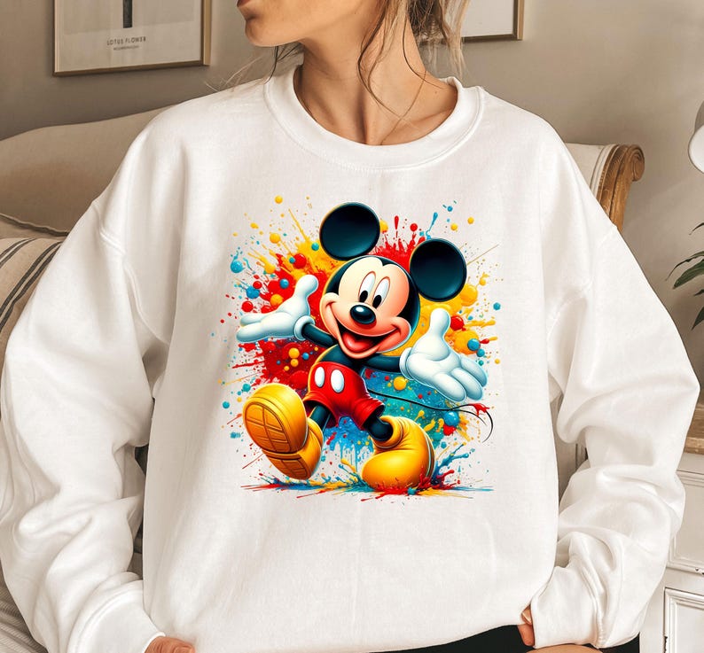 a woman wearing a sweatshirt with a mickey mouse painting on it
