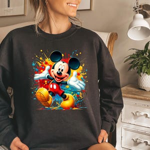 a woman wearing a mickey mouse sweatshirt in a bedroom