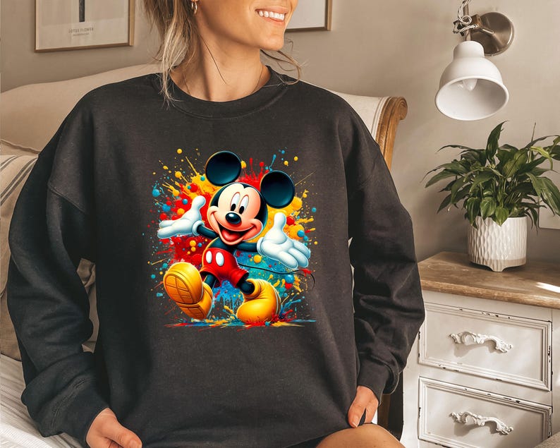 a woman wearing a mickey mouse sweatshirt in a bedroom