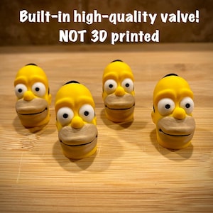 Può includere: Quattro coprivalvole gialli a forma di testa di personaggio dei cartoni animati, con capelli neri e bocca marrone chiaro. Il testo "Built-in high-quality valve! NOT 3D printed" è sopra.