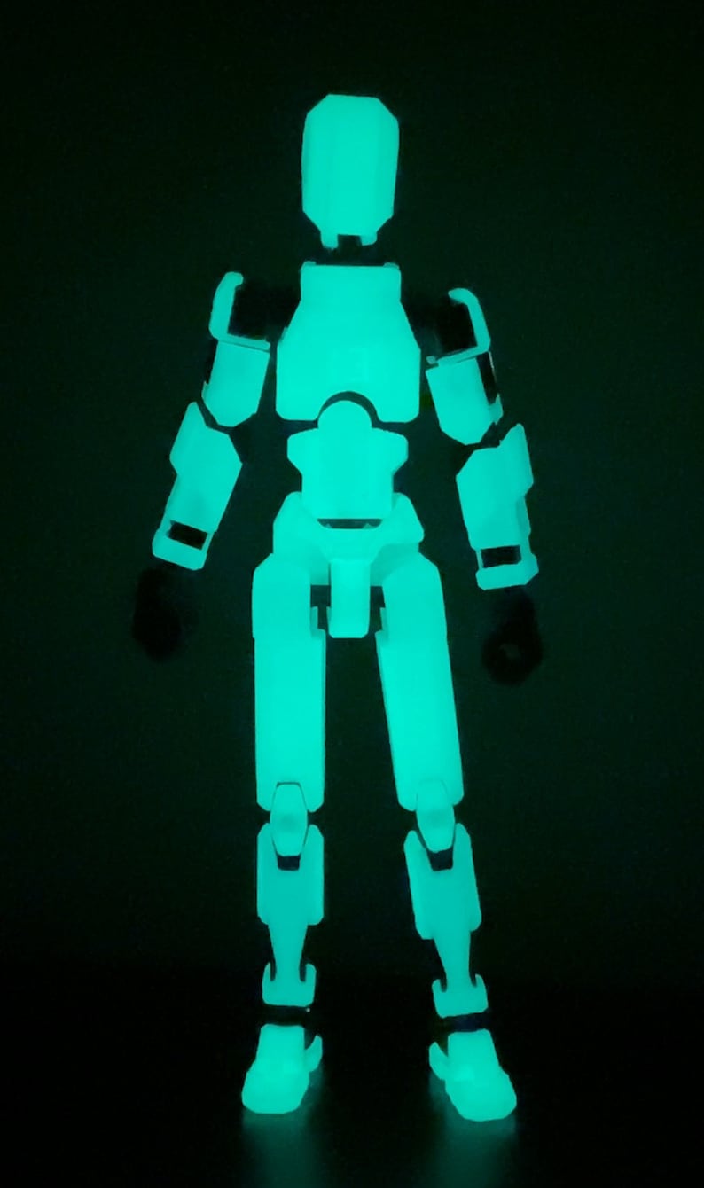 May include: A glow-in-the-dark articulated action figure with a white body and black joints. The figure is standing with its arms at its sides and its legs slightly apart.