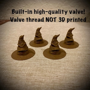 May include: Four brown, cone-shaped hats with a wide brim and a folded, wrinkled texture. The text above reads: Built-in high-quality valve! Valve thread NOT 3D printed. These items feature a pointed top and a circular base, resembling a classic wizard hat.