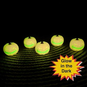 May include: Five glowing jack-o'-lanterns with carved, green, spooky faces. The pumpkins are yellow and have black stems. A yellow starburst with red trim and the words "Glow in the Dark" is in the lower right corner.