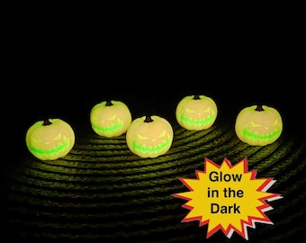 May include: Five glowing jack-o'-lanterns with carved, green, spooky faces. The pumpkins are yellow and have black stems. A yellow starburst with red trim and the words "Glow in the Dark" is in the lower right corner.