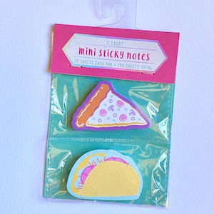 May include: A package of mini sticky notes featuring food-themed designs. The package includes a pizza slice and a taco. The packaging is pink and teal, with the words "mini sticky notes" printed on the front.