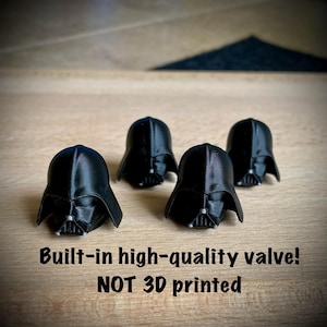 Op de afbeelding: Vier zwarte Darth Vader helm miniaturen. De helmen zijn gerangschikt op een lichtbruin houten oppervlak. De tekst "Built-in high-quality valve! NOT 3D printed" is zichtbaar onderaan de afbeelding.