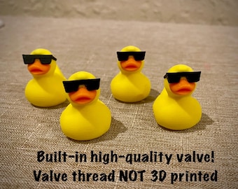May include: Four yellow rubber ducks with orange beaks, each wearing black rectangular sunglasses. The text below reads: Built-in high-quality valve! Valve thread NOT 3D printed. These small figures are arranged in a group on a textured surface.