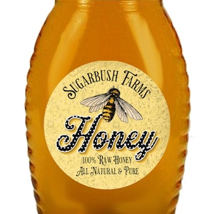 May include: A glass jar of honey with a yellow and black label that reads "Sugarbush Farms Honey 100% Raw Honey All Natural & Pure". The label features a stylized bee with black and yellow stripes.