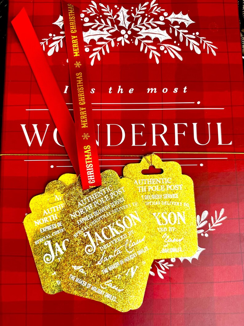 Puede incluir: Un fondo a cuadros rojo y blanco con una cinta roja que dice "Merry Christmas". Etiquetas de regalo doradas y brillantes con el texto "Authentic North Pole Post" y "Jackson" est&aacute;n unidas a la cinta. El fondo dice "Wonderful".