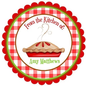 May include: Red and white checkered circle with a green border and scalloped edges. The circle has the text "From the Kitchen of:" and a red pie with a brown crust and red filling. The text "Amy Matthews" is below the pie.