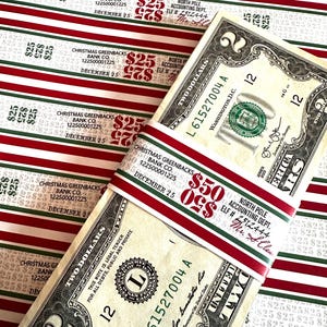May include: A bundle of two-dollar bills wrapped with a red and green band that reads "$50" and "Christmas Greenbacks Bank Co." The background features wrapping paper with red and white stripes and text.