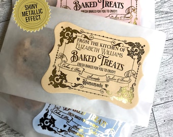 May include: Two gold foil labels with a vintage design. The labels say "From the kitchen of Elizabeth Williams Baked Treats Fresh Baked for you to enjoy! Cakes & Pies Sweets Cookies & Bread Homemade".
