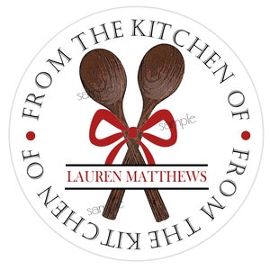 May include: A circular sticker design featuring two crossed brown wooden spoons tied with a red ribbon. The text FROM THE KITCHEN OF is printed in a circular border, and the name LAUREN MATTHEWS is centered in red text between two black lines.