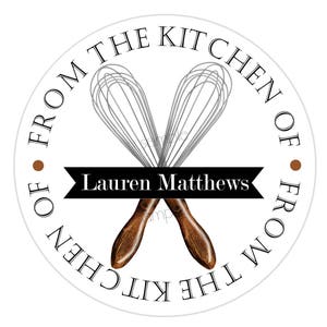 Pode incluir: Etiqueta redonda branca com texto preto que diz "From the Kitchen of" e "From the Kitchen of" em um c&iacute;rculo ao redor de dois batedores de arame prateados cruzados com al&ccedil;as de madeira marrom. O texto "Lauren Matthews" est&aacute; em uma faixa preta.