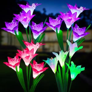 May include: A collection of illuminated artificial flowers in various colors, including purple, pink, and green. The flowers have a glowing effect, with green stems and leaves. The background is dark, suggesting nighttime.