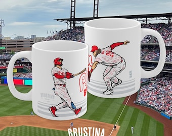May include: Two white ceramic mugs with baseball-themed illustrations. The mug on the left shows a baseball player in a red and white uniform swinging a bat. The mug on the right shows a baseball player in a red and white uniform throwing a ball. Both mugs have the text "BRUSTINA" and "PHI SHOP PA est. 2024" printed on them.