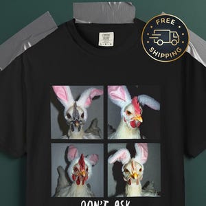 May include: Black t-shirt with a four-panel image of chickens in bunny ears. The text "DON'T ASK" is printed in white below the images. The shirt has a Comfort Colors tag.