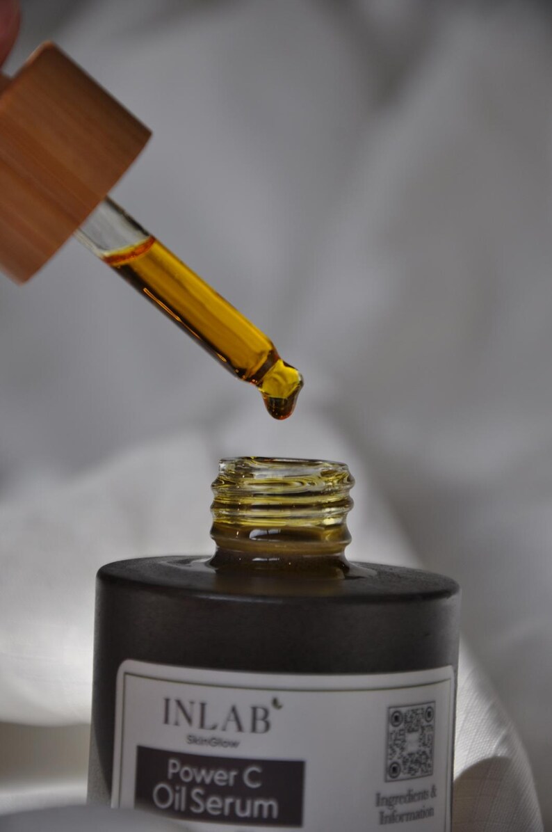 May include: A dark brown glass bottle with a dropper filled with a yellow liquid. The bottle is labelled "INLAB' SkinGlow Power C Oil Serum".