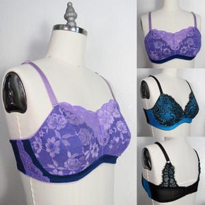 May include: A collection of bras in various colors and styles displayed on mannequins. The bras feature lace detailing in shades of purple, teal, and black. The bras have adjustable straps and underwire support. The overall aesthetic is feminine and delicate.