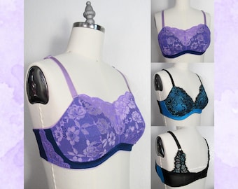 May include: A collection of bras in various colors and styles displayed on mannequins. The bras feature lace detailing in shades of purple, teal, and black. The bras have adjustable straps and underwire support. The overall aesthetic is feminine and delicate.