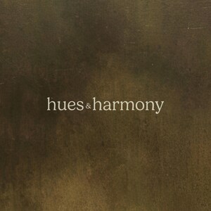 May include: A textured, dark brown background with the text "hues & harmony" in white.