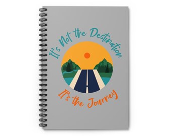 May include: A gray spiral notebook with the text "It's Not the Destination It's the Journey" in orange and blue text. The notebook features a graphic of a road with mountains and a sun in the background.