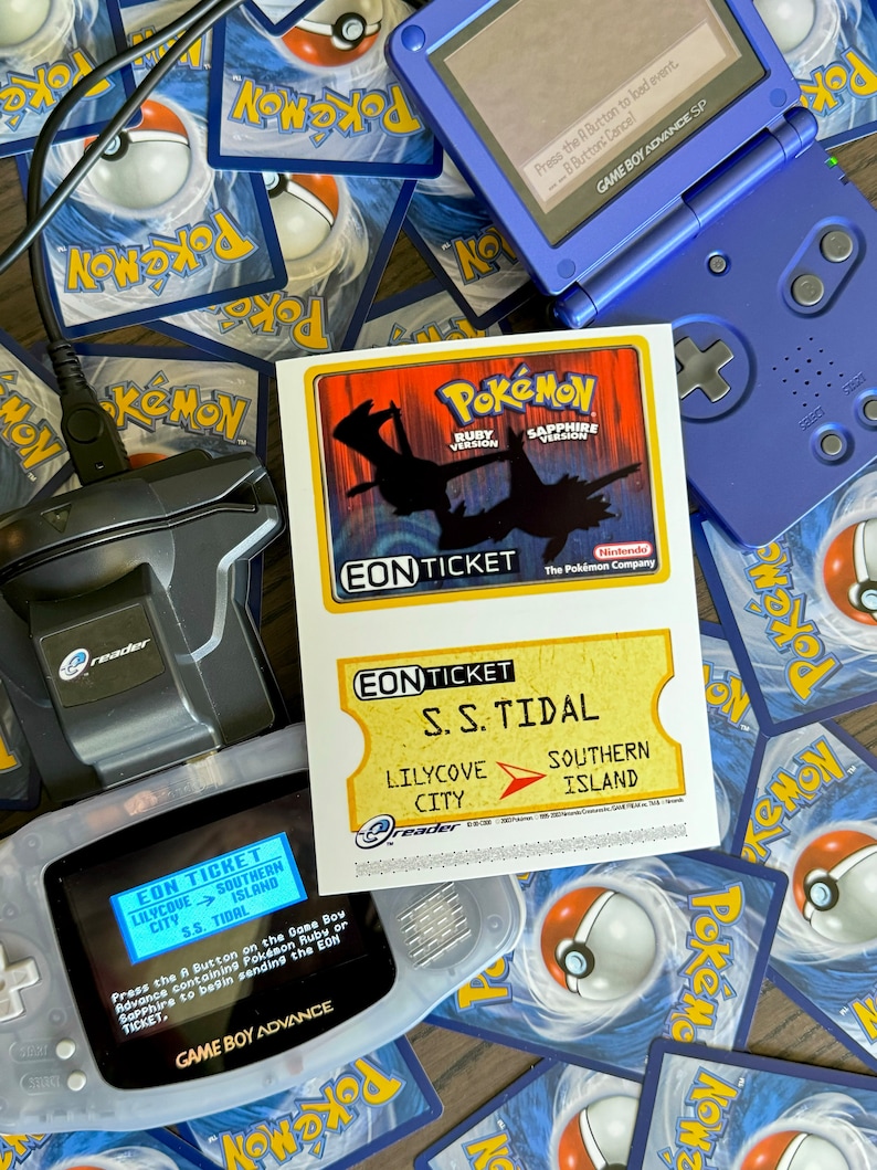 May include: A blue Game Boy Advance SP with a screen displaying a Pokemon Eon Ticket for the S.S. Tidal, which takes players from Lilycove City to Southern Island. The ticket is for Pokemon Ruby and Sapphire versions. The Game Boy is on top of a pile of Pokemon trading cards.
